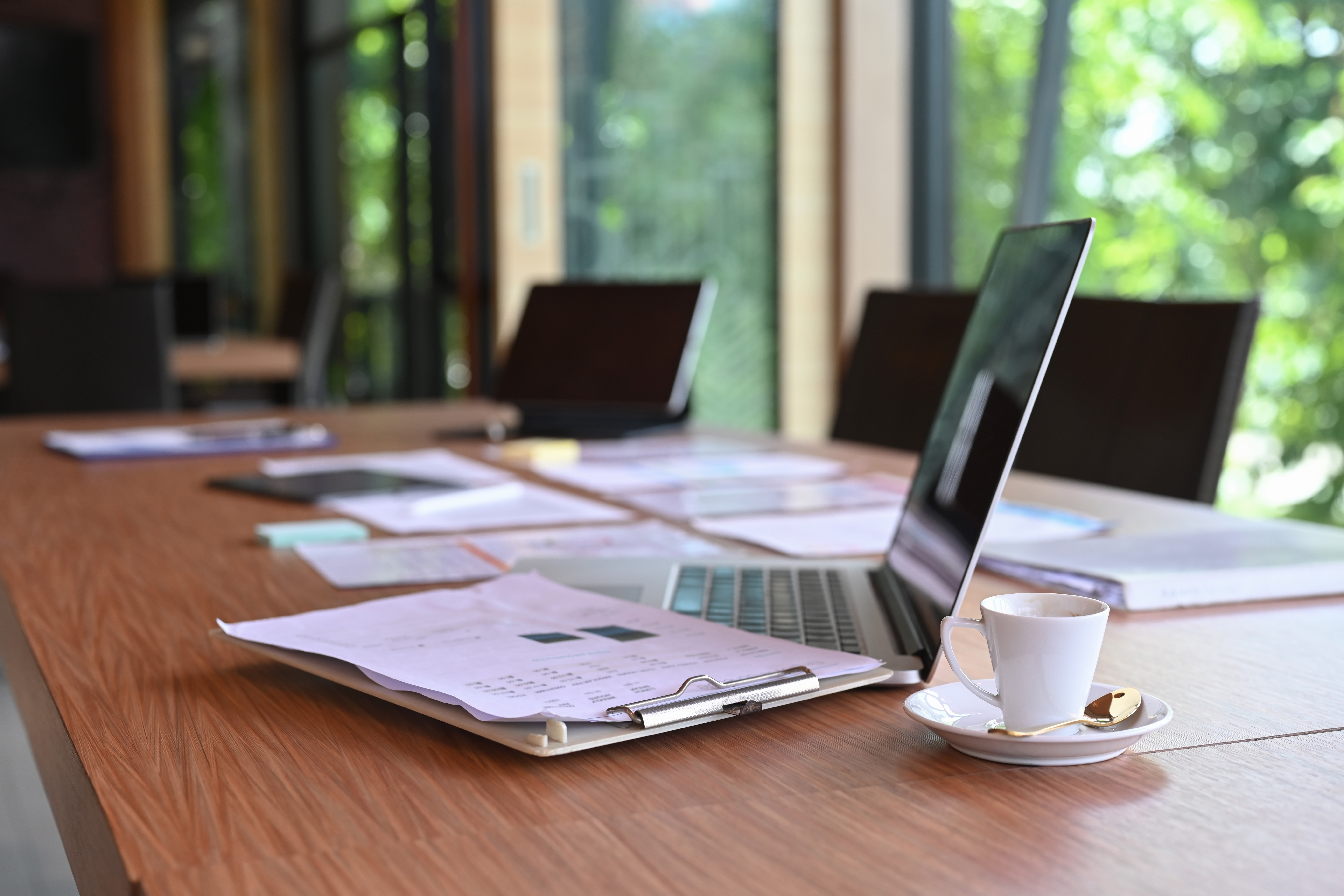 Computer laptop, documents and coffee cup on wooden table.